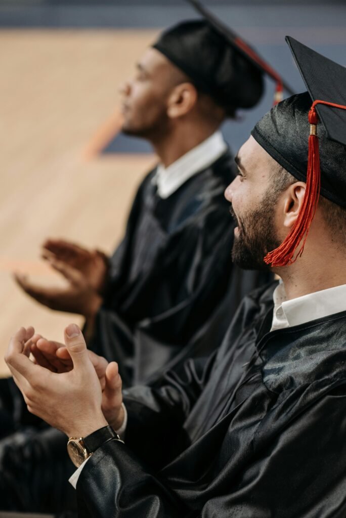 A joyful moment at a graduation ceremony with graduates clapping in their caps and gowns.
